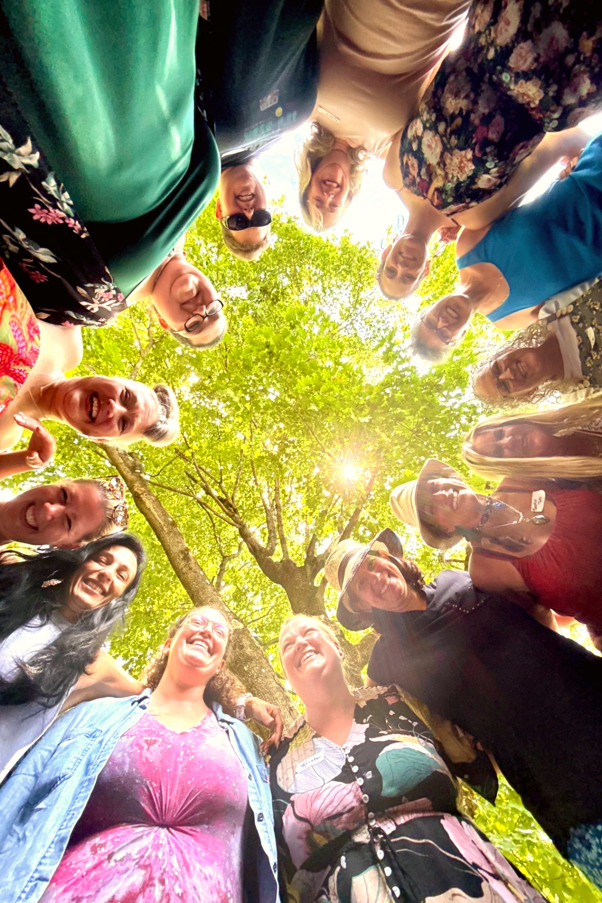 A circle of joyful women gathered beneath the trees for the Held Sacred sisterhood