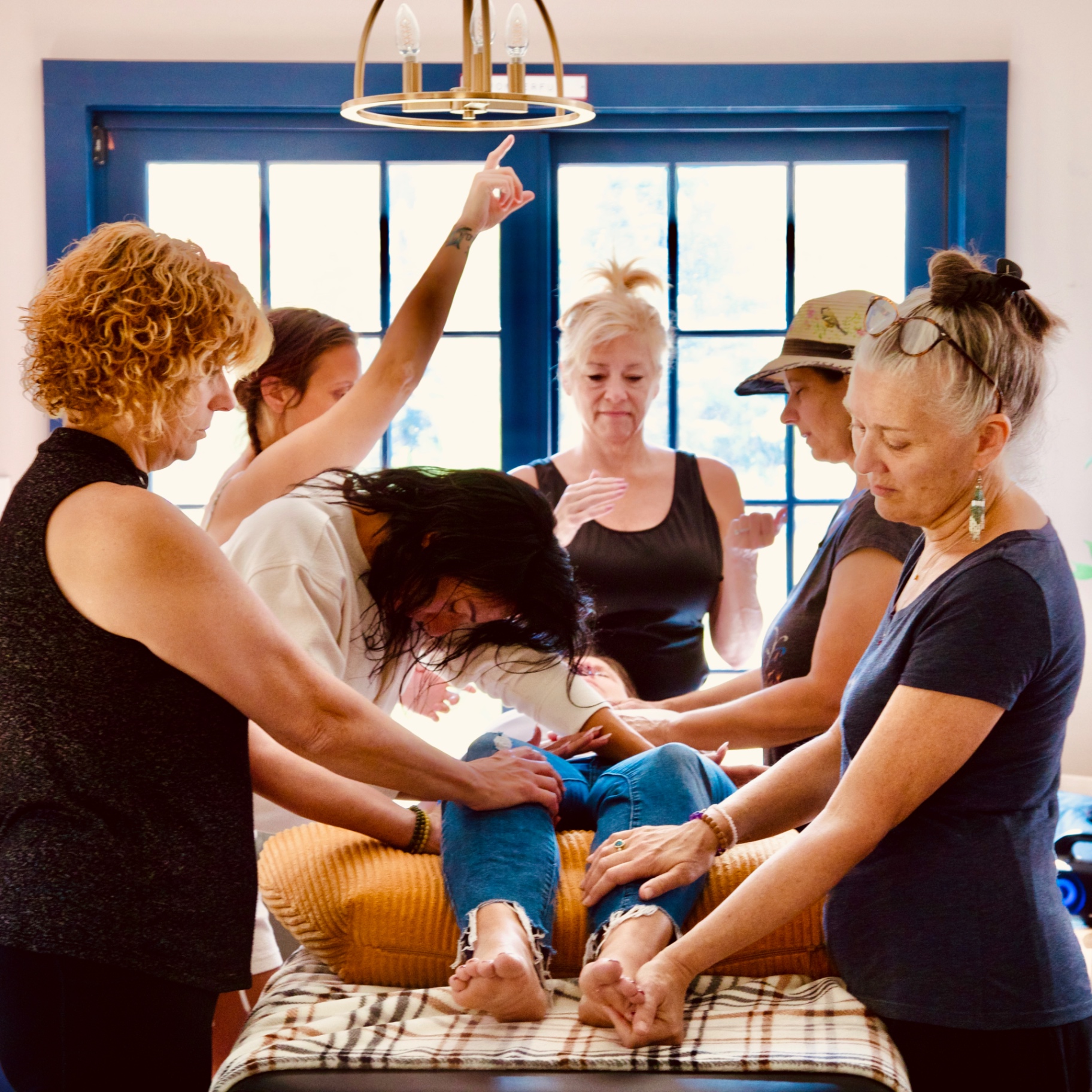 Held Sacred sisters offering hands-on energy healing to a woman on a table