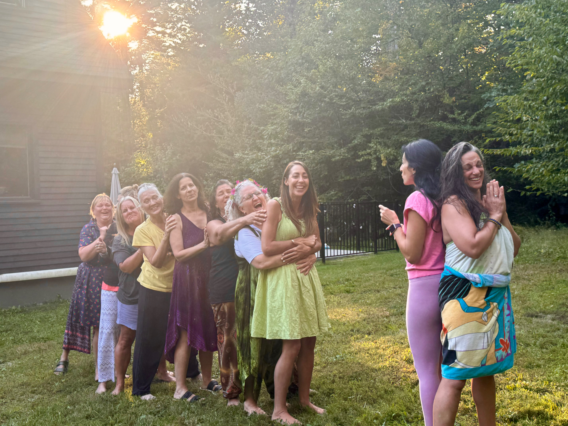 Held Sacred sisters laughing in a playful line together in golden evening light