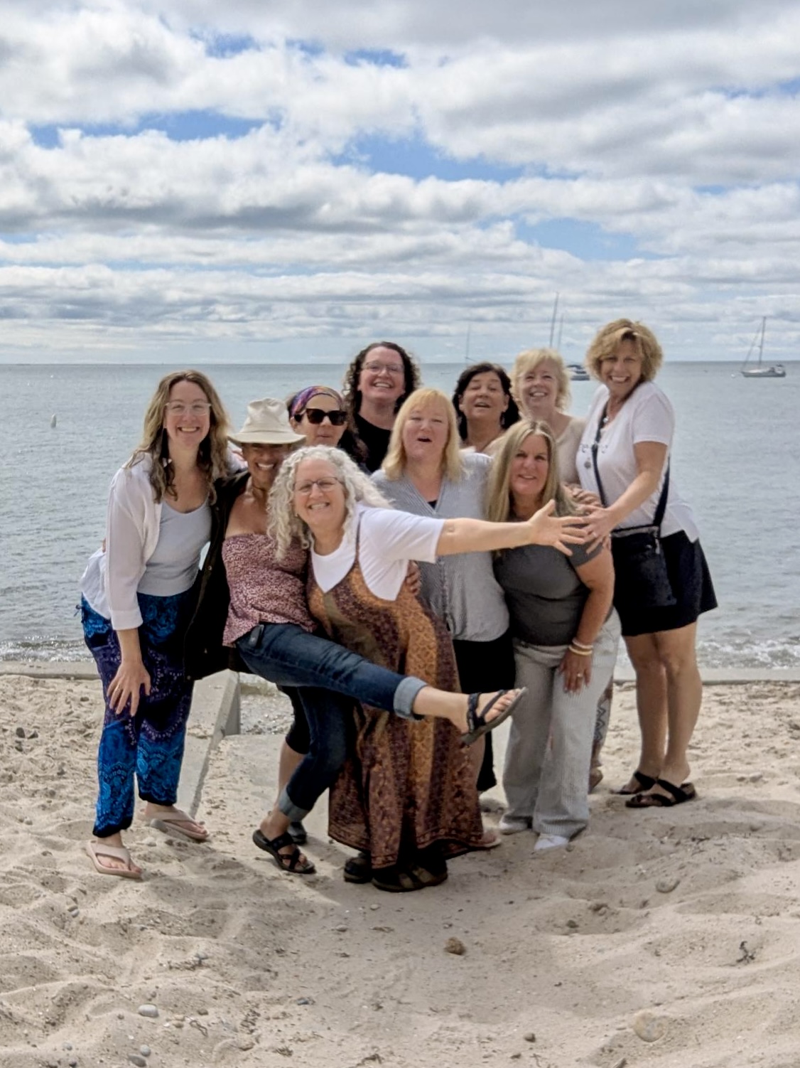 Held Sacred sisters laughing together on the beach by the water