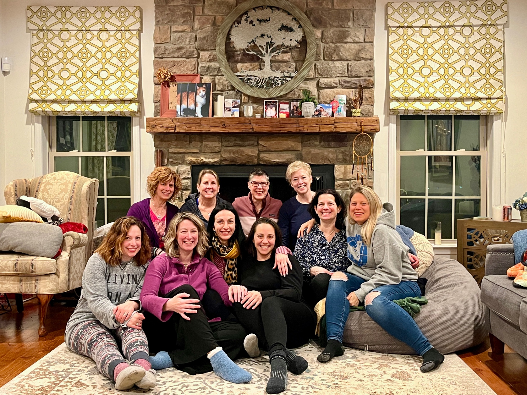 Held Sacred sisters gathered together by the fireplace, smiling
